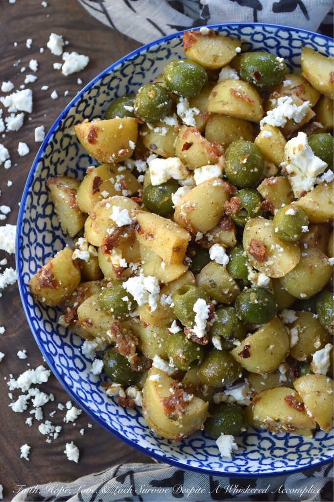 Green Olive & Sun Dried Tomato Potato Salad - Mayonnaise-based potato salads don't always fare well in the sweltering heat of a humid afternoon, so this summer, we’re ditching the mayo in favor of something much brighter, bolder, and infinitely more delicious. This Italian-inspired potato salad with whole pitted green olives and feta cheese is easy to make, holds up perfectly at a barbecue or picnic, and packs a rather serious flavor punch. By infusing olive oil with sun-dried tomatoes, dried herbs, and seasonings, this dressing transforms tender, boiled baby yellow potatoes into a side dish that will have everyone reaching for seconds.
