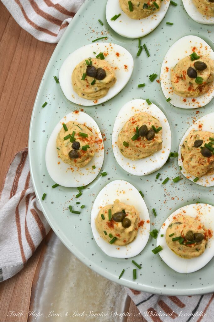 Deviled Eggs with Lemon Caper Remoulade - These flavorful deviled eggs take things to the next level with a zesty, homemade lemon caper remoulade. With a bright punch of lemon zest and the perfect salty bite of capers, these appetizer cuties are about to become the star of every backyard barbecue. And, thanks to a touch of heat, these deviled eggs are anything but ordinary. Finished with a dusting of paprika, a garden-fresh garnish of chives, and a few whole non-pareil capers, these lil' bites are guaranteed to disappear practically the moment you set them down.