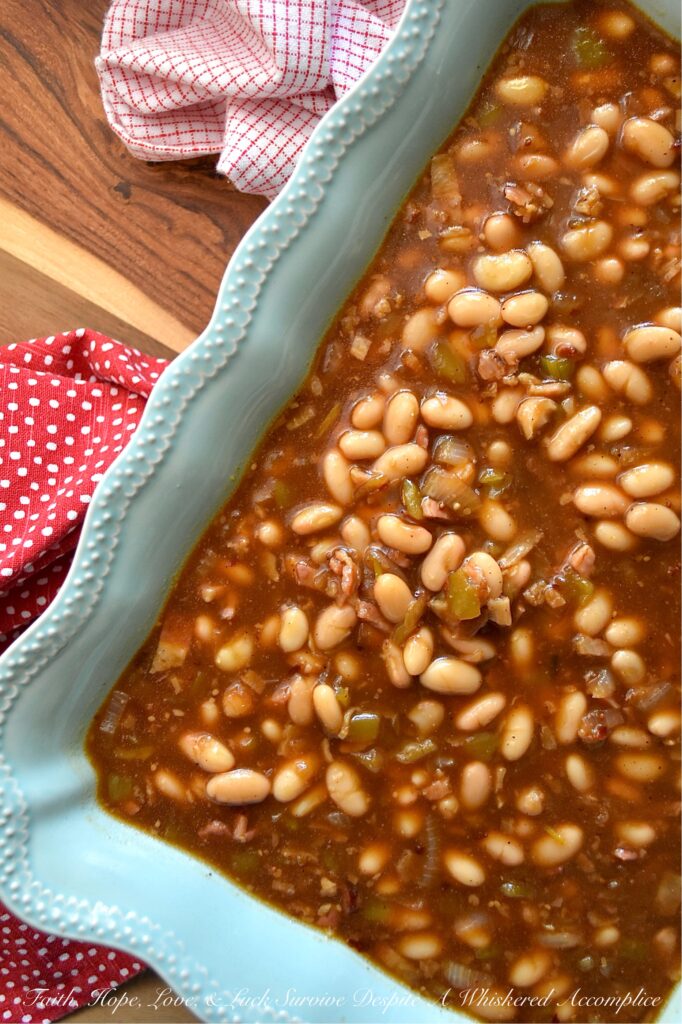 Smoky Baked Beans with Green Chiles & Bacon - Most store-bought baked beans are overly sweet, mushy, and entirely forgettable. This recipe, however, uses canned Great Northern Beans. Elevating them with a quick and easy homemade sauce. Between the smoky bacon, the subtle heat of green chiles, and the deep, wood-fired flavor from a generous splash of liquid smoke, these beans are practically addictive. They're thick, sticky, smoky, and best of all? You can prep them days in advance, making this side dish the perfect stress-free secret weapon for your next backyard barbecue or picnic.