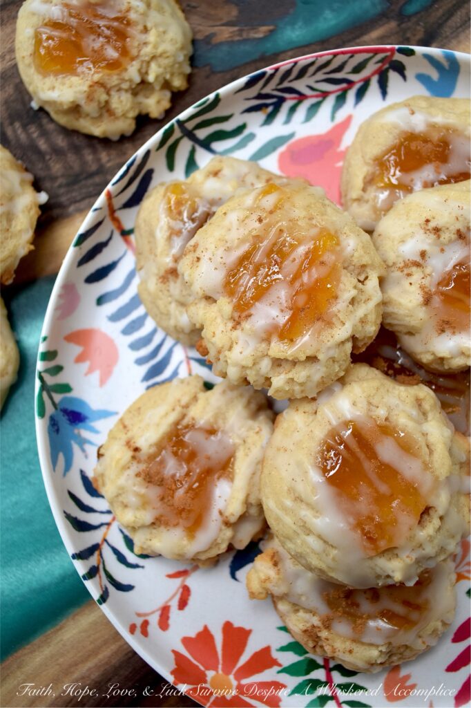 Peaches and Cream Rustic Thumbprint Cookies - Craving a taste of summer all year long? These buttery, fruity cream cheese thumbprint cookies are pretty much sunshine in a bite. With a gooey peach preserves center, a splash of peach schnapps in the icing, and enough cinnamon warmth to add just the right amount of spice, these peaches and cream rustic thumbprint cookies are addictively dangerous. Whether you’re pairing them with morning coffee or evening tea, these jammy cookies are proof that summer never really has to end.