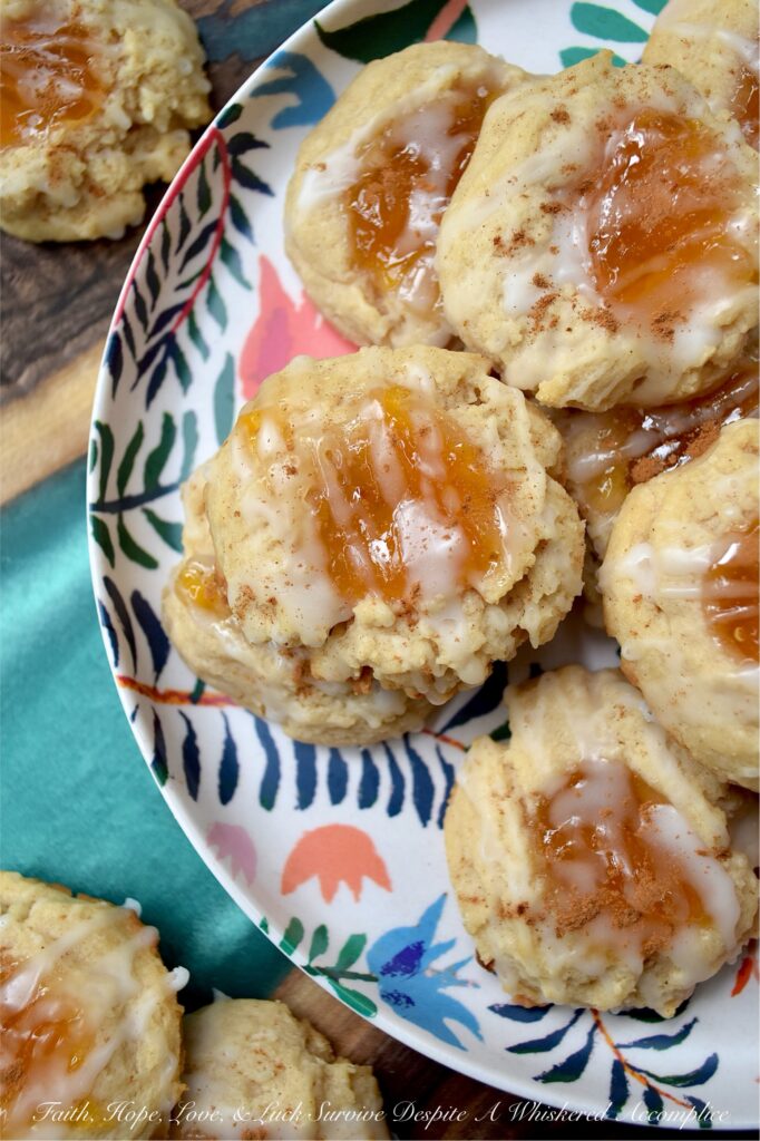 Peaches and Cream Rustic Thumbprint Cookies - Craving a taste of summer all year long? These buttery, fruity cream cheese thumbprint cookies are pretty much sunshine in a bite. With a gooey peach preserves center, a splash of peach schnapps in the icing, and enough cinnamon warmth to add just the right amount of spice, these peaches and cream rustic thumbprint cookies are addictively dangerous. Whether you’re pairing them with morning coffee or evening tea, these jammy cookies are proof that summer never really has to end.