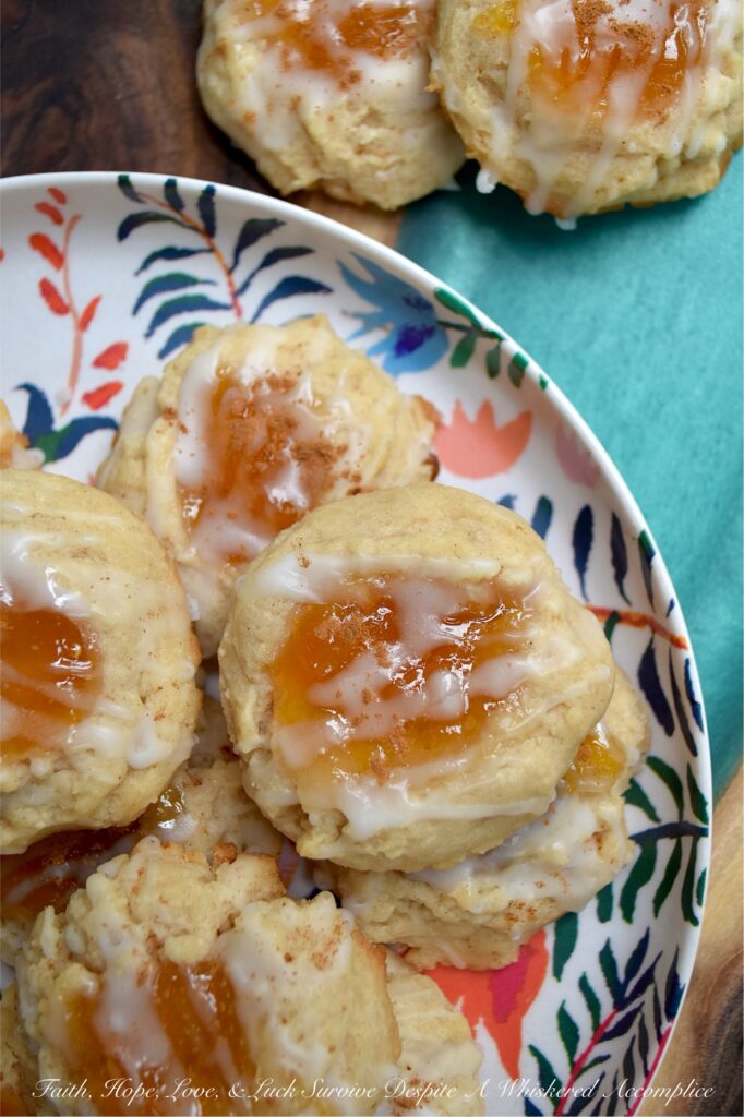 Peaches and Cream Rustic Thumbprint Cookies - Craving a taste of summer all year long? These buttery, fruity cream cheese thumbprint cookies are pretty much sunshine in a bite. With a gooey peach preserves center, a splash of peach schnapps in the icing, and enough cinnamon warmth to add just the right amount of spice, these peaches and cream rustic thumbprint cookies are addictively dangerous. Whether you’re pairing them with morning coffee or evening tea, these jammy cookies are proof that summer never really has to end.