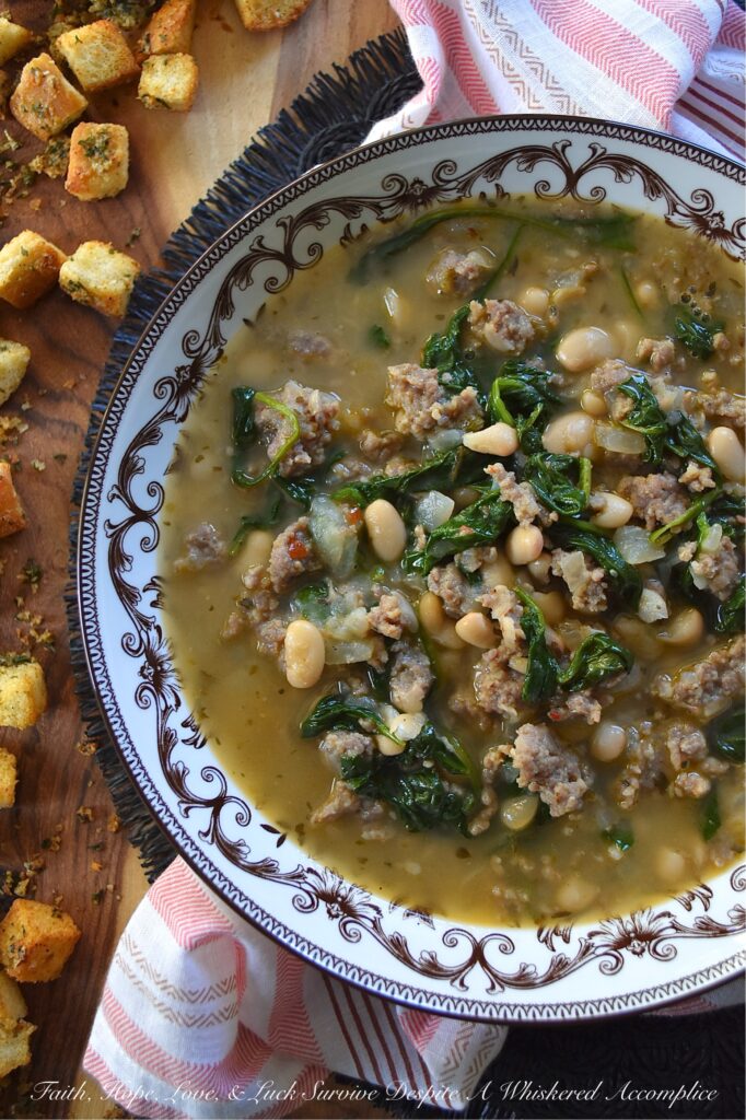 Weeknight Italian Sausage & Spinach Bean Soup - Loaded with savory mild Italian sausage, creamy canned beans, and tender baby spinach, this Italian herb-infused soup is simple to make, budget-friendly, and easy to adapt. You can use homemade or store-bought chicken broth, or even add more vegetables like carrot, butternut squash, or sweet potato. Finish this bean soup with a generous sprinkle of freshly grated Parmesan or a handful of crunchy, simple homemade baked croutons for an effortless one-pot meal that turns a chaotic weeknight into a cozy night in.