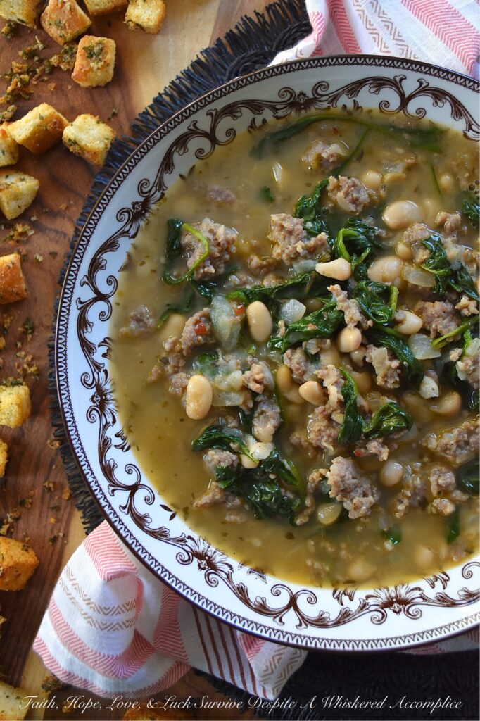 Weeknight Italian Sausage & Spinach Bean Soup - Loaded with savory mild Italian sausage, creamy canned beans, and tender baby spinach, this Italian herb-infused soup is simple to make, budget-friendly, and easy to adapt. You can use homemade or store-bought chicken broth, or even add more vegetables like carrot, butternut squash, or sweet potato. Finish this bean soup with a generous sprinkle of freshly grated Parmesan or a handful of crunchy, simple homemade baked croutons for an effortless one-pot meal that turns a chaotic weeknight into a cozy night in.