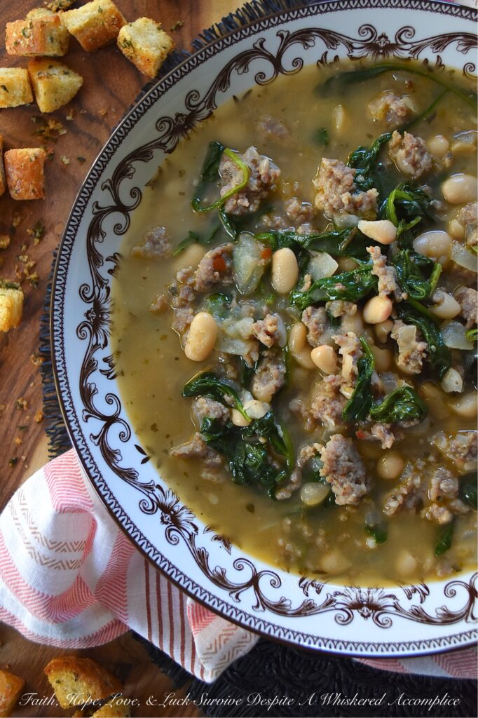 Weeknight Italian Sausage & Spinach Bean Soup - Loaded with savory mild Italian sausage, creamy canned beans, and tender baby spinach, this Italian herb-infused soup is simple to make, budget-friendly, and easy to adapt. You can use homemade or store-bought chicken broth, or even add more vegetables like carrot, butternut squash, or sweet potato. Finish this bean soup with a generous sprinkle of freshly grated Parmesan or a handful of crunchy, simple homemade baked croutons for an effortless one-pot meal that turns a chaotic weeknight into a cozy night in.
