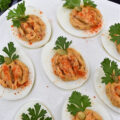 Bacon & Paprika Pumpkin Deviled Eggs - When you're searching for an autumn party deviled egg recipe that not only tastes amazing but looks festive, this is the recipe you need. Not only do crispy bacon and paprika add tons of flavor, as well as texture, but parsley leaves and roasted salted pumpkin seeds give these little pumpkin-shaped deviled eggs the perfect fall party appearance. They're the perfect excuse to throw a party.