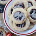 Raspberry-Cranberry Thumbprint Shortbread Cookies - These festive raspberry and cranberry thumbprint cookies, topped with a simple powdered sugar vanilla glaze, are a delicious treat that combines buttery, sweet, and fruity flavors to make them utterly irresistible. And, with the ability to use any brand or variety of mixed berry jam, jelly, or preserves, you can create an array of different flavors for your cookie tray or platter. Whether you bake these cookies for a special occasion or just because you're craving something sweet, they're sure to be a hit.