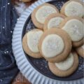 Snowy Eggnog Melt-Away Cookies - One bite of these sweet buttery melt-in-your-mouth cookies, and you'll be transported to a winter wonderland. With their dusting of white sparkling sugar snow, simple eggnog and powdered sugar icing, and warm nutmeg and cinnamon spices, these Snowy Eggnog Melt-Away Cookies are the ideal treat for the chilly holiday season.